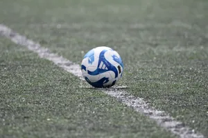 Close-up of a blue and white soccer ball resting on a lined green turf field. jigsaw puzzle