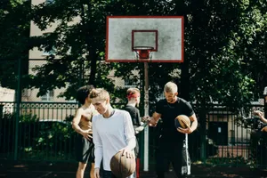 Group of adults playing basketball on an outdoor court during the day. jigsaw puzzle