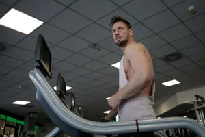 Low angle of muscular adult male athlete in sportswear during training on running machine in modern spacious fitness center while looking away jigsaw puzzle