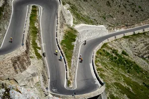 Cyclists biking along winding mountain road curves with scenic views. jigsaw puzzle