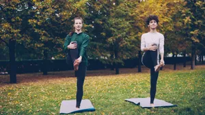 Two women doing yoga on mats in a fall park, surrounded by colorful trees. jigsaw puzzle