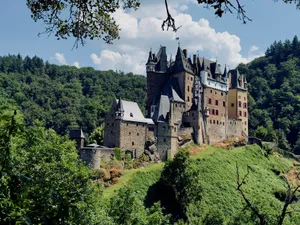 Eltz Castle stands majestically amidst lush green forests in Wierschem, capturing its historic charm on a bright summer day. jigsaw puzzle