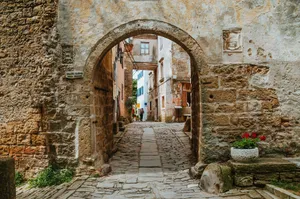 Charming cobblestone street view through ancient archway in old town. A picturesque scene of European architecture. jigsaw puzzle