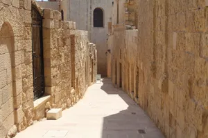 Explore a sunlit ancient stone alleyway lined with historic buildings, exuding timeless architectural charm. jigsaw puzzle