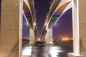 A beautiful shot of a modern bridge illuminated with colored lights over a river at night. jigsaw puzzle