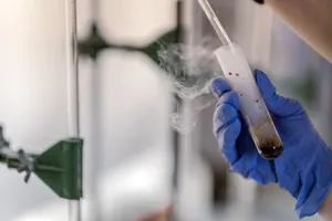 Close-up of a gloved hand holding a steaming test tube in a laboratory setting. jigsaw puzzle
