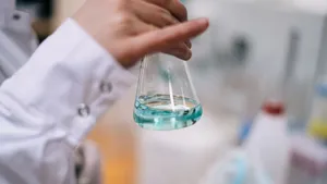 Close-up of a scientist holding a glass flask with colored liquid in a laboratory. jigsaw puzzle
