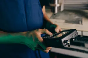 Close-up of technician using a handheld control device in a manufacturing setting. jigsaw puzzle
