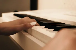 A close-up view of a hand with painted nails gently playing piano keys, creating a serene musical moment. jigsaw puzzle