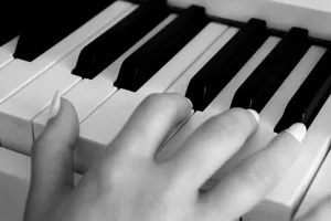 Elegant close-up shot of a hand playing piano keys in black and white, highlighting musical expression. jigsaw puzzle
