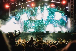 Vibrant music concert with DJ and crowd at night, showcasing lively atmosphere and dazzling lights. jigsaw puzzle