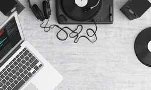 Flat lay of a music workspace with a laptop, headphones, turntable, and speakers on a desk. jigsaw puzzle