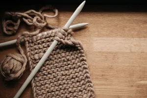 Detailed image of knitting needles, yarn, and a knitting project on a wooden table. jigsaw puzzle