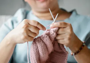 Crop mature female resting at home and knitting with pink yarn and needles jigsaw puzzle