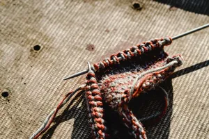 Detailed view of knitting work with needles and colorful yarn on textured surface. jigsaw puzzle