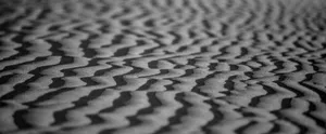 Monochrome close-up of wind-sculpted desert sand patterns in soft focus. jigsaw puzzle