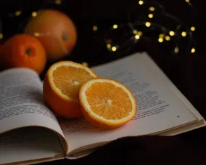 Oranges on an open book with fairy lights create a warm, cozy scene. jigsaw puzzle