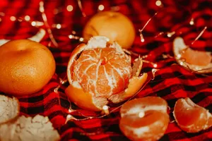 Close-up of peeled and whole clementines on a checkered blanket with string lights. jigsaw puzzle