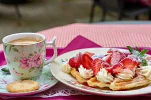Delight in a breakfast of Belgian waffles with strawberries and a floral coffee cup on a cozy table setting. jigsaw puzzle