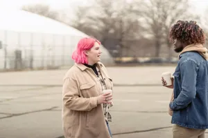 Plus size woman with pink hair enjoying coffee to go and talking with African American man while standing on city street on autumn day jigsaw puzzle