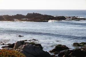Rocky coastline with gentle waves under a clear sky jigsaw puzzle