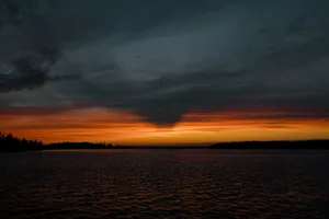 a sunset over a body of water with trees in the background jigsaw puzzle