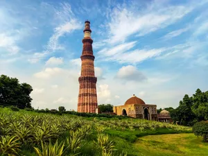 Qutub minar stands tall under a bright, cloudy sky. jigsaw puzzle
