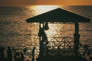 Silhouettes of people in the water near a wooden pavilion at low sun. jigsaw puzzle
