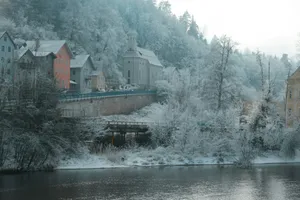 Snow-covered buildings on a hill overlooking a river. jigsaw puzzle