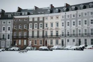 Row of townhouses covered in snow with cars parked jigsaw puzzle