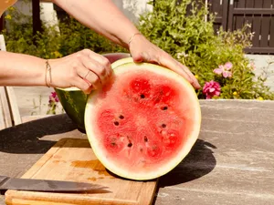 a person cutting up a watermelon on a cutting board jigsaw puzzle