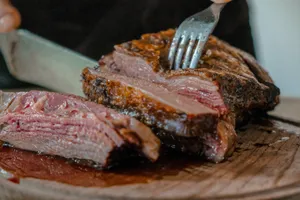 person slicing a meat on brown wooden board jigsaw puzzle