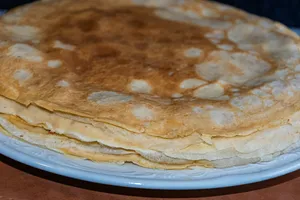 Stack of thin, golden crepes on a white plate. jigsaw puzzle