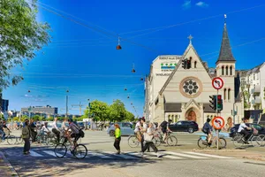 People cycling and crossing street near church jigsaw puzzle
