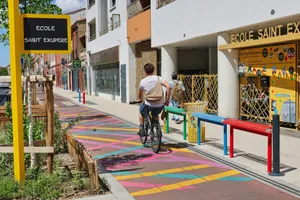 A person cycling on a colorful path past a school. jigsaw puzzle