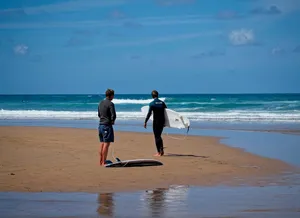 man and woman holding white surfboard walking on beach during daytime jigsaw puzzle