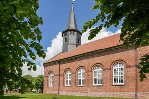 A brick church with a steeple framed by green leaves. jigsaw puzzle