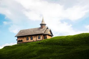 Small wooden church on a grassy hill under sky. jigsaw puzzle