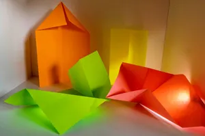 Colorful origami shapes arranged on a white surface. jigsaw puzzle