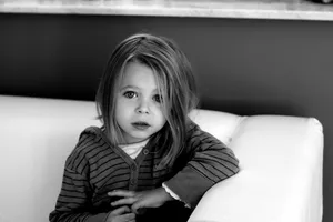 a little girl sitting on top of a white couch jigsaw puzzle