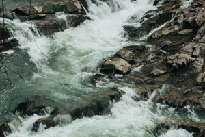 Dynamic river rapids flowing over rugged rocks, showcasing nature's power and beauty. jigsaw puzzle