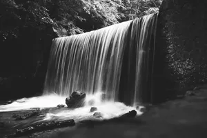 A serene black and white image of a waterfall cascading over rocks with flowing water. jigsaw puzzle