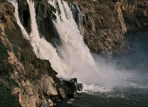 Stunning waterfall plunging over rugged cliffs into a misty pool below, capturing nature's raw power. jigsaw puzzle