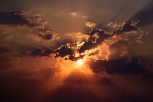 Stunning sunset with dramatic sunbeams piercing through clouds, set against a vivid sky. jigsaw puzzle