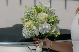 A close-up of a bride's hand holding a beautiful white bouquet with roses and lilies. jigsaw puzzle