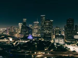 Aerial view of a vibrant city skyline at night with illuminated skyscrapers and roads. jigsaw puzzle