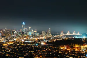 Aerial view of megapolis with residential district located near modern skyscrapers and suspension bridge at night jigsaw puzzle