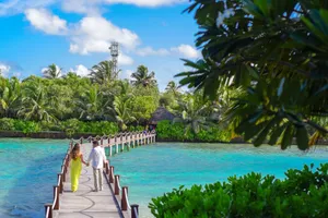 Couple holding hands on a boardwalk in paradise with turquoise water and lush greenery. jigsaw puzzle