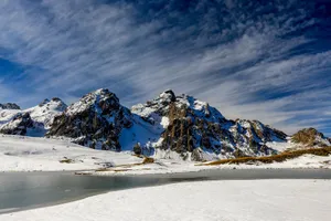 Stunning view of snow-capped mountains and iced lake in Valloire, France under a vibrant blue sky. jigsaw puzzle
