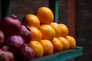 A vibrant display of fresh ripe oranges and pomegranates at an outdoor market stall. jigsaw puzzle